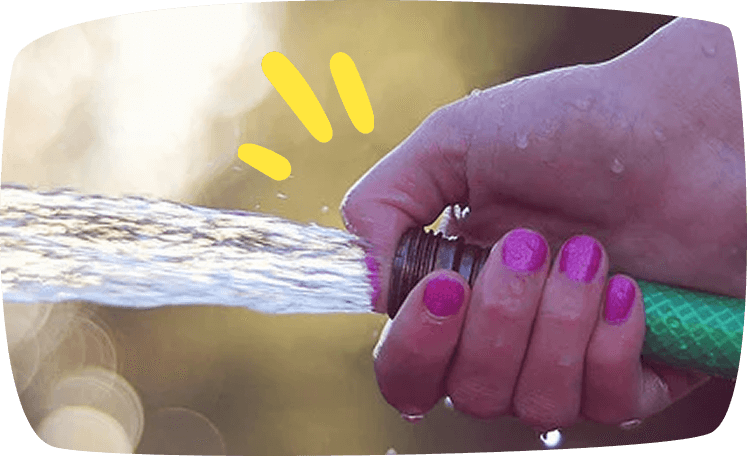 A hand with bright pink nail polish gripping a garden hose spraying water.
